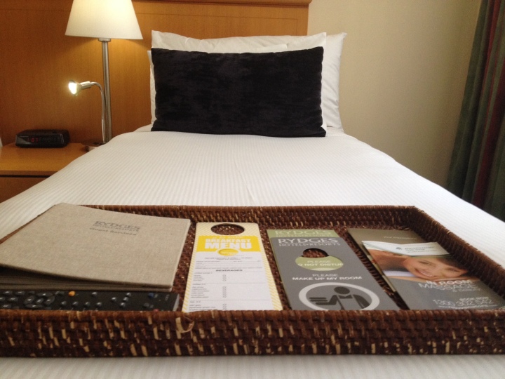 One of the single beds with a welcome information pack of the hotel